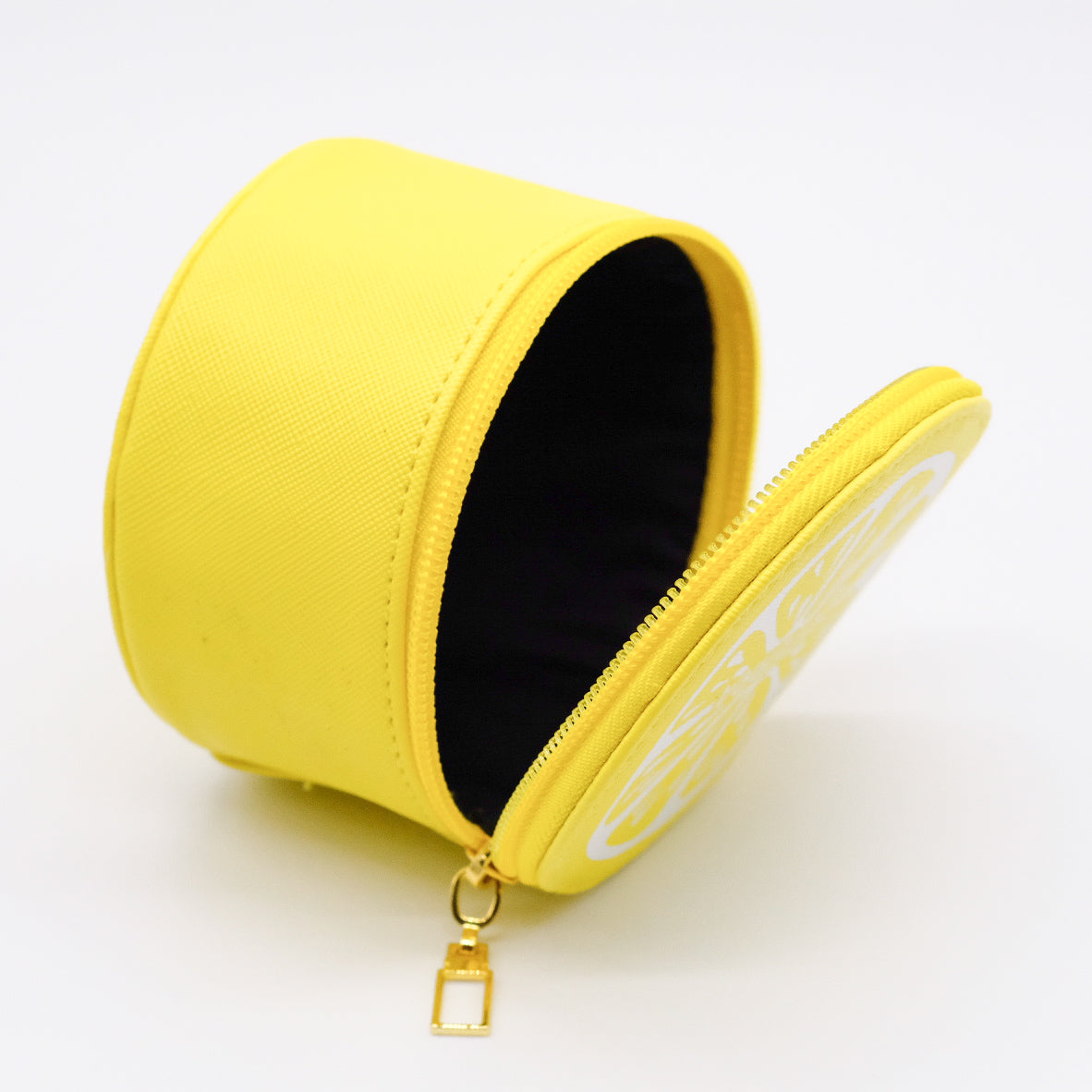 Étui rond jaune doTERRA ouvert, avec fermeture éclair dorée, intérieur noir et motif de tranche de citron sur le couvercle.