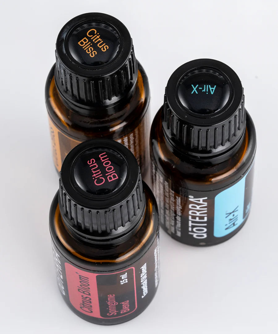 Vue en plongée de trois bouteilles d’huiles essentielles doTERRA avec collants sur les bouchons identifiant Citrus Bliss, Air-X et Citrus Bloom.