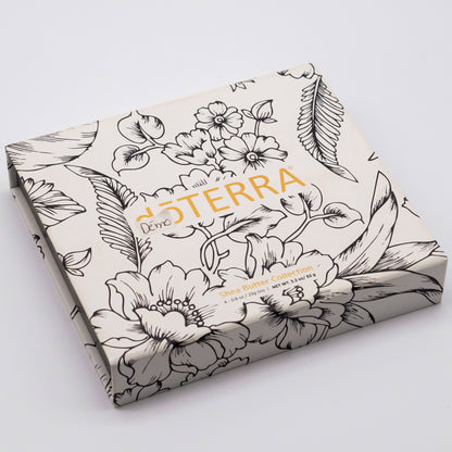 Coffret fermé blanc doTERRA Collection beurre de karité, avec logo doré et motif floral noir.