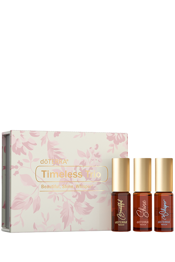 Coffret Timeless Trio de doTERRA avec trois rouleaux à bille Beautiful, Shine et Whisper Touch, présenté devant son emballage floral rose.