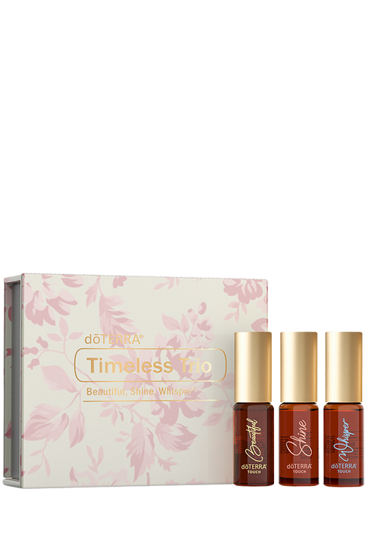 Coffret Timeless Trio de doTERRA avec trois rouleaux à bille Beautiful, Shine et Whisper Touch, présenté devant son emballage floral rose.