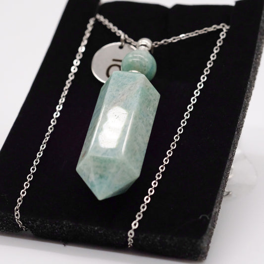 Collier pendentif en amazonite doTERRA avec flacon, présenté sur un support noir.