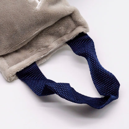 Détail de la sangle bleu foncé du coussin thermique doTERRA, fixée à une housse douce grise.