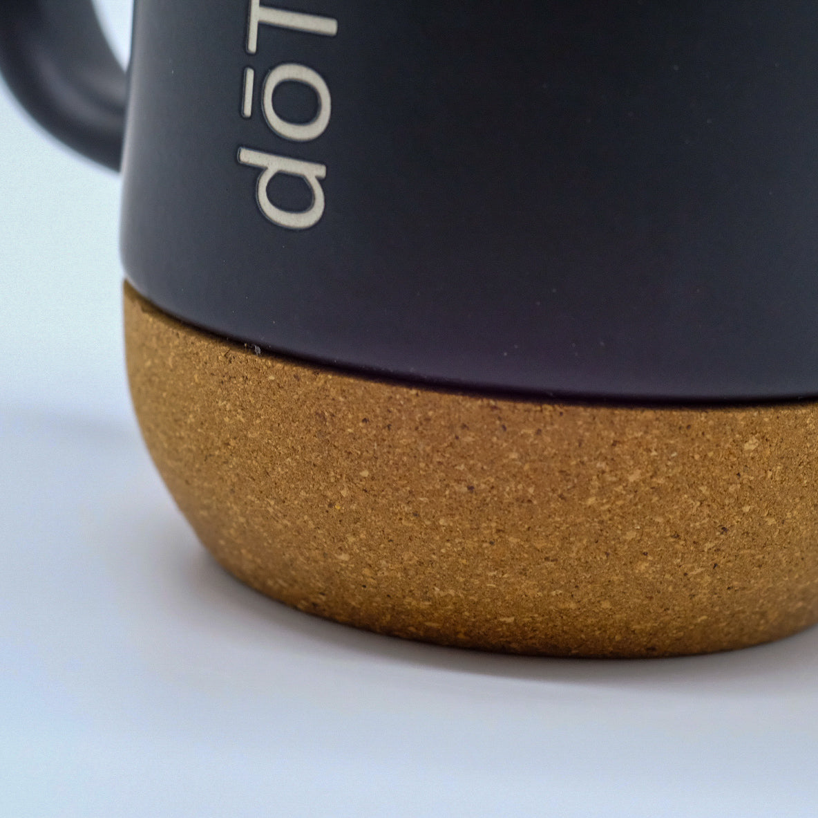 Gros plan sur la base en liège d’une tasse noire doTERRA.