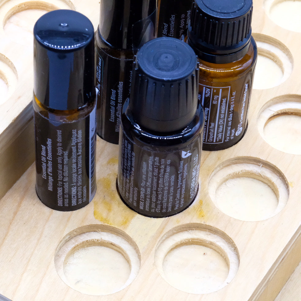 Gros plan sur des bouteilles et rouleaux à bille doTERRA placés dans un présentoir en bois à emplacements ronds.