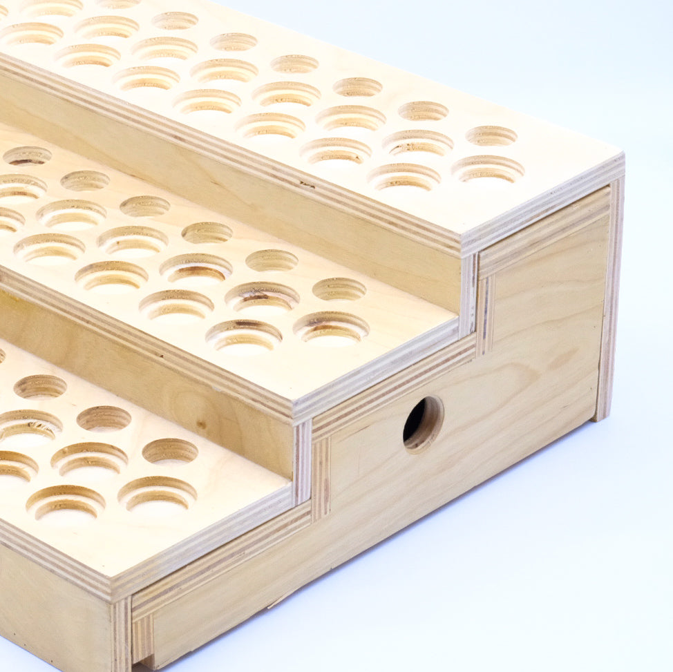 Gros plan sur le côté d’un présentoir en bois à 3 niveaux pour huiles essentielles, avec ouverture ronde de tiroir.