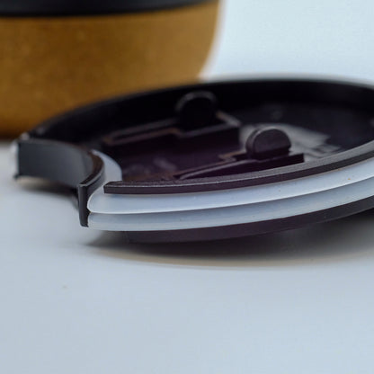 Gros plan sur le couvercle d’une tasse doTERRA, avec la base en liège visible en arrière-plan.