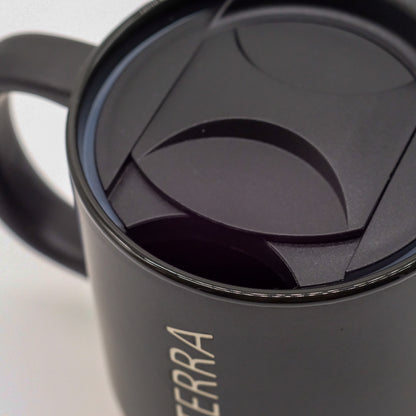 Gros plan sur le couvercle noir et la poignée d’une tasse doTERRA noire.