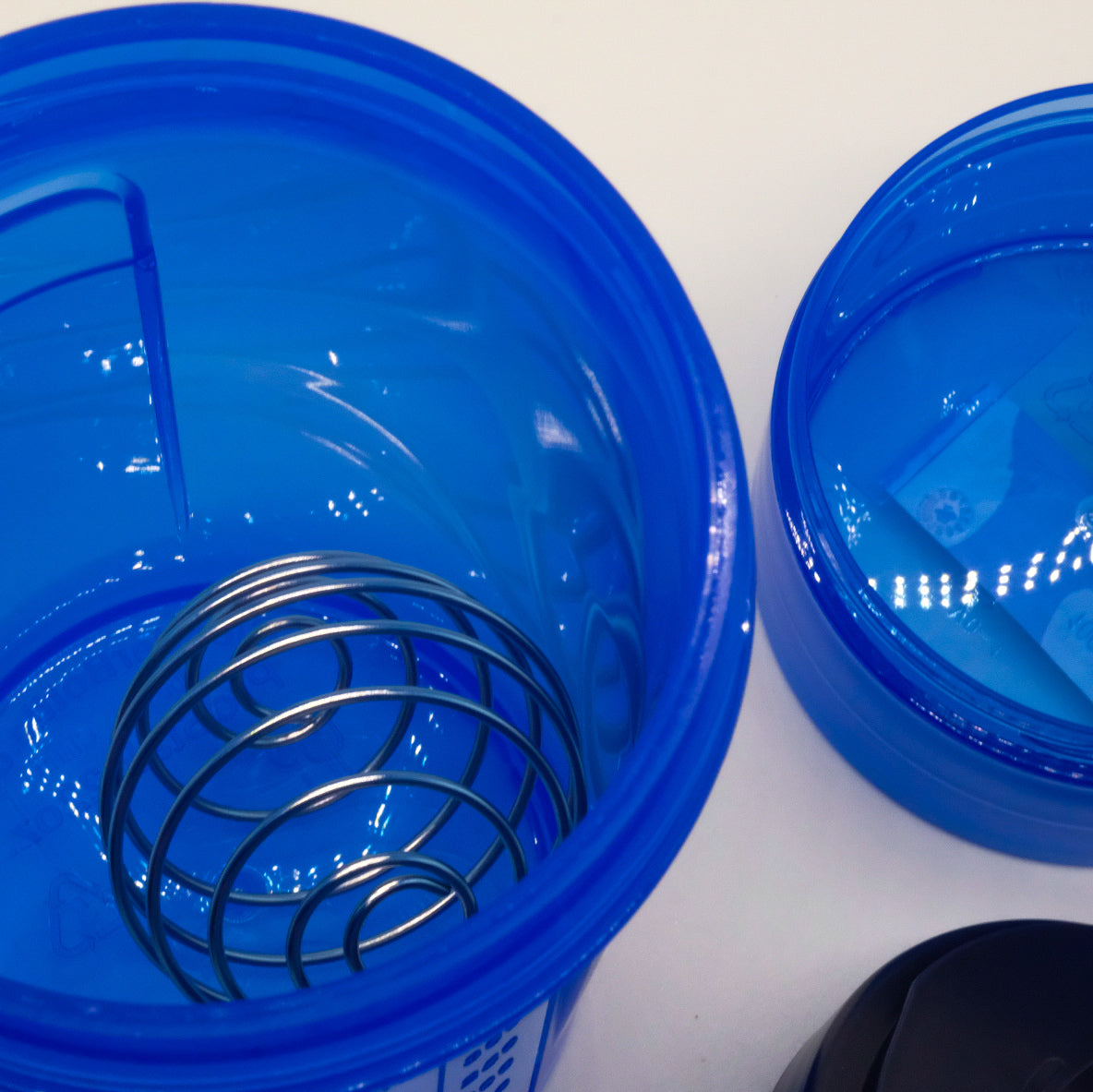 Gros plan sur l’intérieur d’un shaker bleu doTERRA avec fouet bille en métal et compartiment bleu à côté.