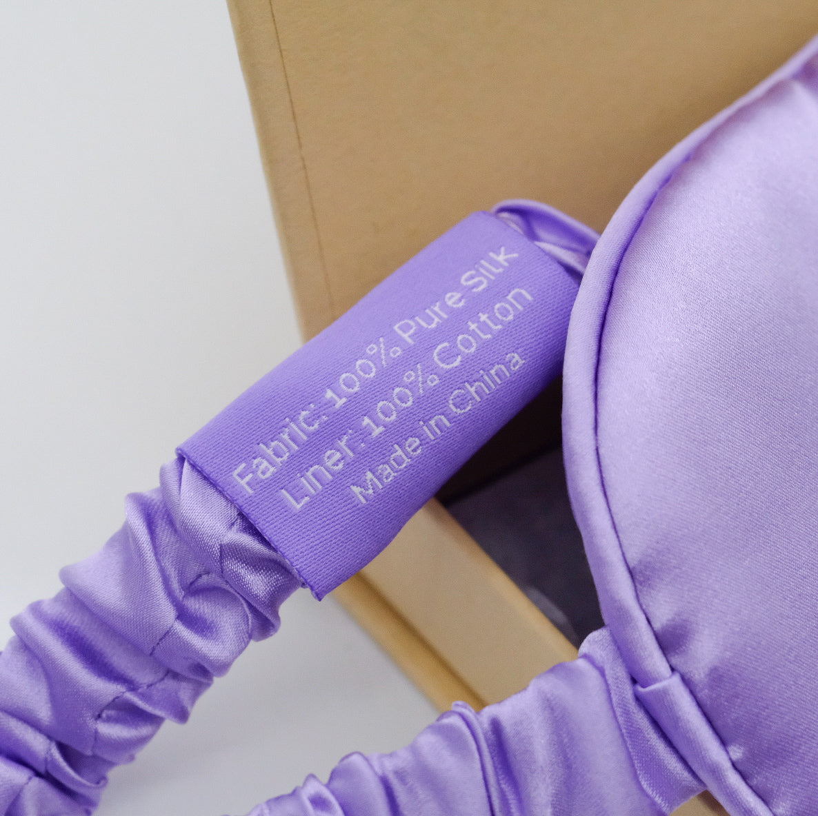 Gros plan sur le masque en soie de mûrier doTERRA lilas, montrant l’élastique satiné et l’étiquette du produit.