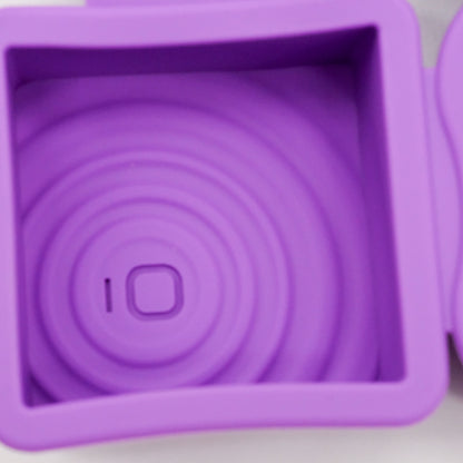 Gros plan sur un moule carré en silicone violet doTERRA avec motif embossé de cercles concentriques au fond.