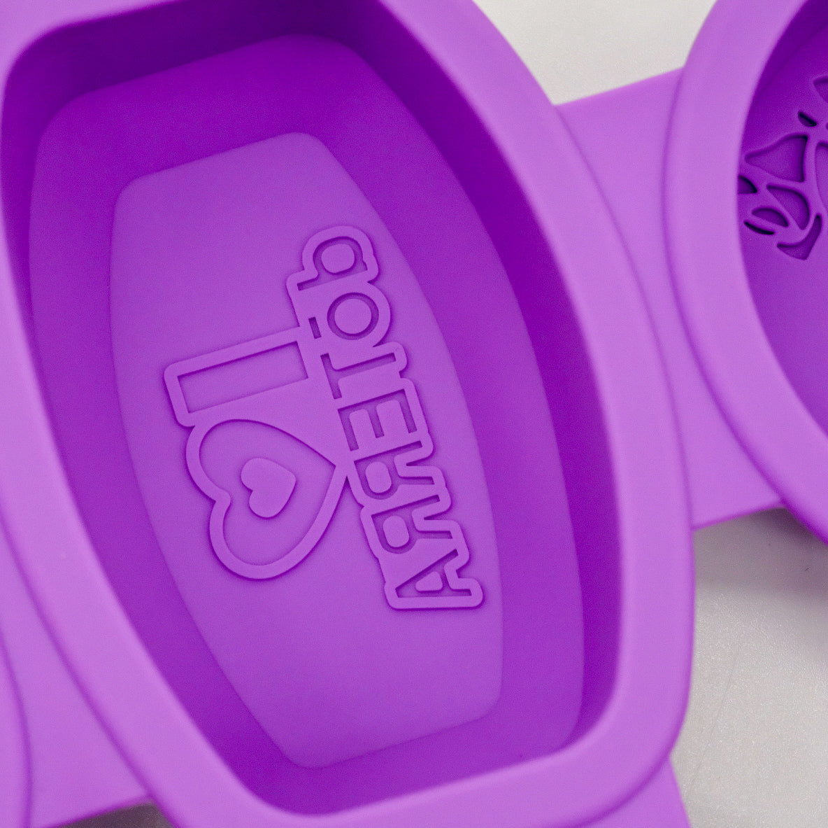 Gros plan sur un moule ovale en silicone violet doTERRA avec motif embossé inversé « j’aime doTERRA ».