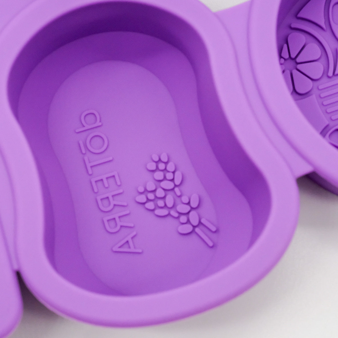 Gros plan sur un moule ovale en silicone violet doTERRA avec motif embossé de lavande et logo au fond.