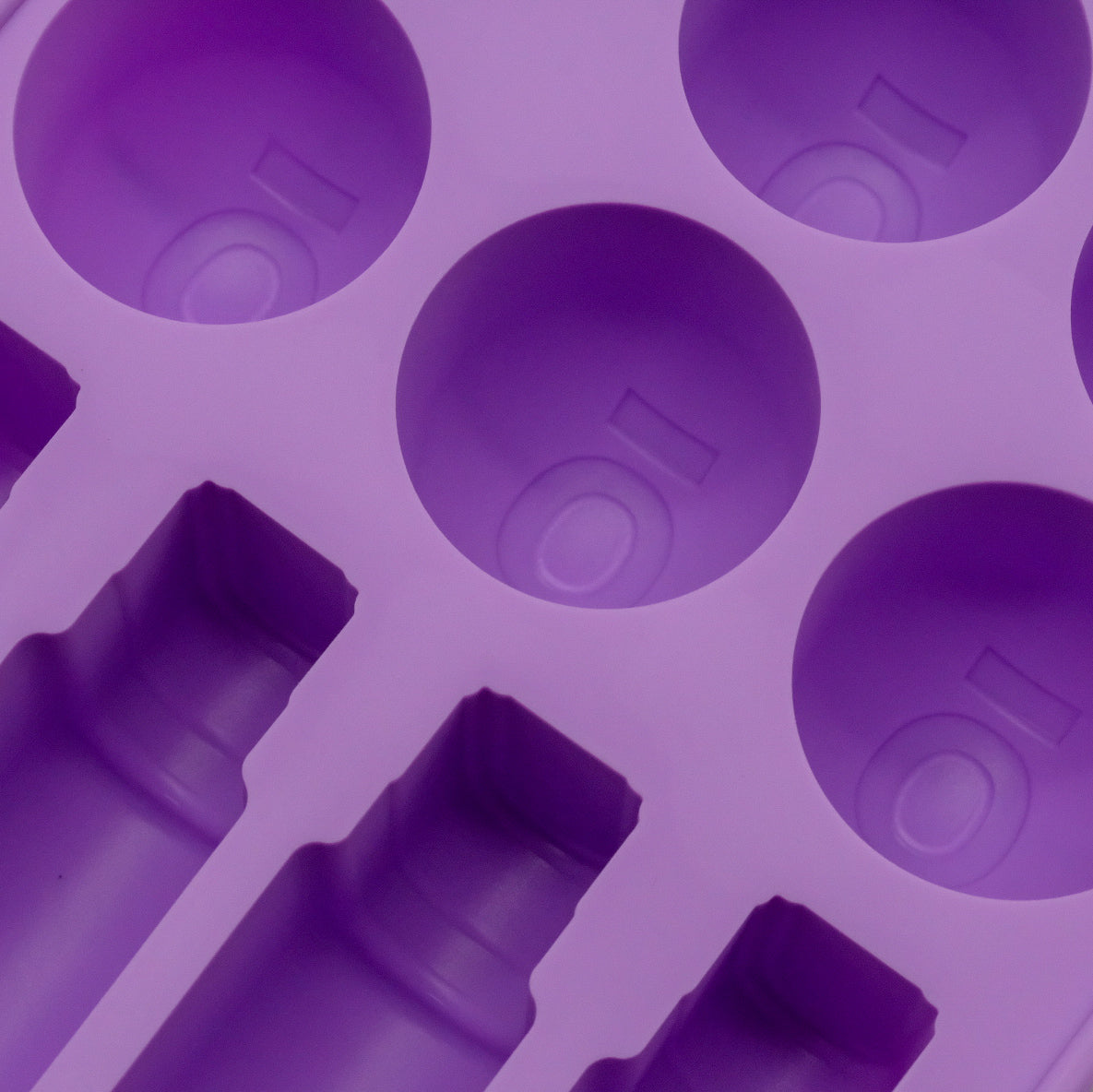 Gros plan sur les empreintes rondes et de flacons d’un moule en silicone violet doTERRA.