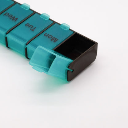 Gros plan sur le pilulier hebdomadaire doTERRA 7 jours à grande capacité, avec un compartiment turquoise ouvert et vide.