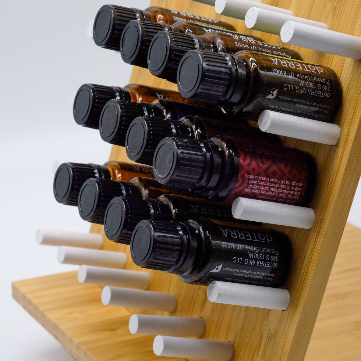 Gros plan sur un présentoir en bambou doTERRA avec plusieurs bouteilles d’huiles essentielles rangées à l’horizontale sur des chevilles blanches.