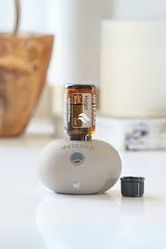 Diffuseur blanc doTERRA avec une huile essentielle insérée sur le dessus et son bouchon posé à côté.