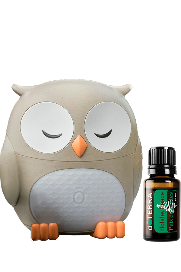 Diffuseur hibou doTERRA beige et blanc avec la synergie Holiday Peace 15 ml placée à côté.