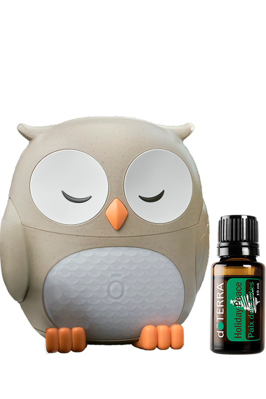 Diffuseur hibou doTERRA beige et blanc avec la synergie Holiday Peace 15 ml placée à côté.