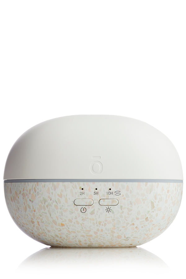 Diffuseur Pebble de doTERRA blanc avec base mouchetée effet terrazzo, vu de face avec boutons de commande et indicateurs de durée.
