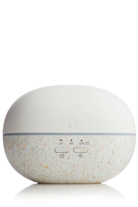 Diffuseur Pebble de doTERRA blanc avec base mouchetée effet terrazzo, vu de face avec boutons de commande et indicateurs de durée.