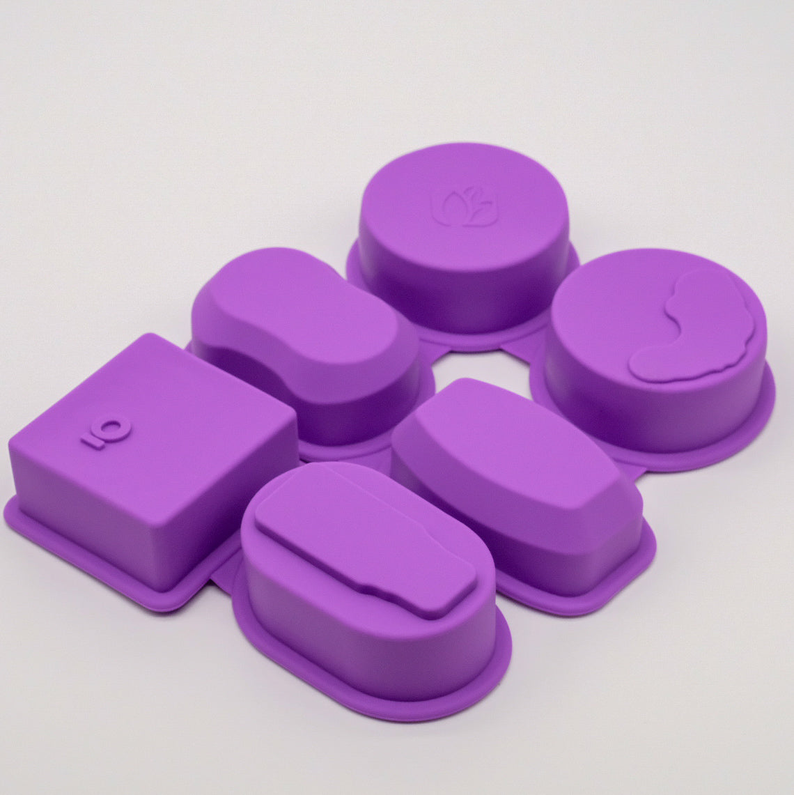 Ensemble de moules en silicone violets doTERRA vus à l’envers, avec différentes formes incluant rondes, ovales et carrée.