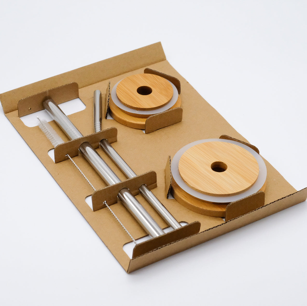 Ensemble réutilisable de couvercles et pailles doTERRA, présenté dans un support en carton avec deux couvercles en bambou, deux pailles métalliques et une brosse de nettoyage.