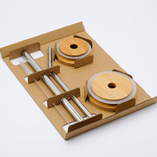 Ensemble réutilisable de couvercles et pailles doTERRA, présenté dans un support en carton avec deux couvercles en bambou, deux pailles métalliques et une brosse de nettoyage.