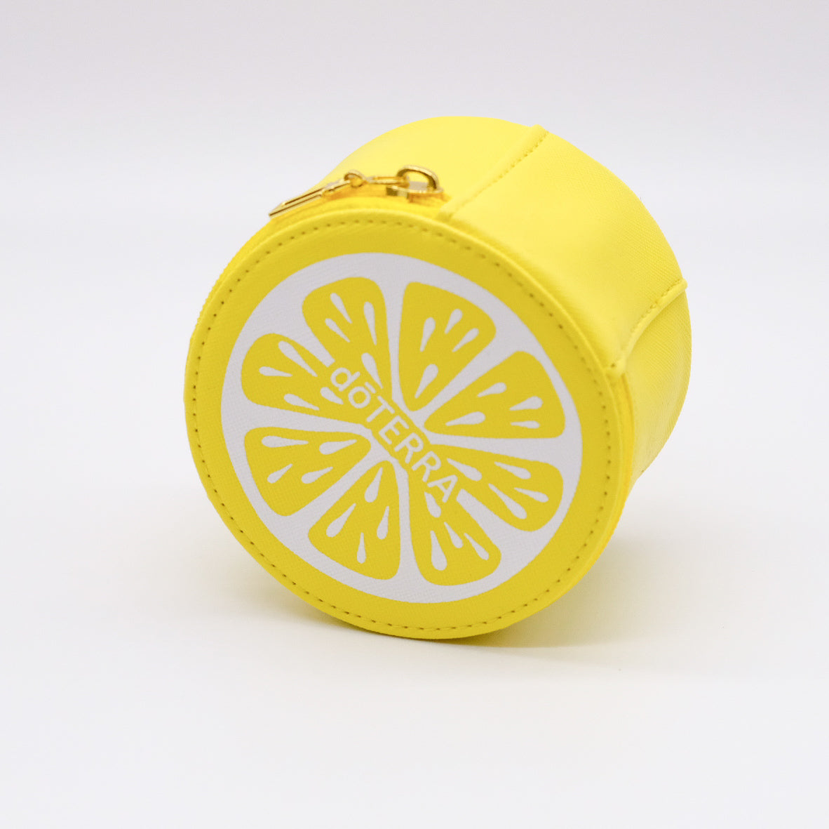 Étui rond jaune doTERRA avec fermeture éclair dorée et motif de tranche de citron blanc sur le devant.