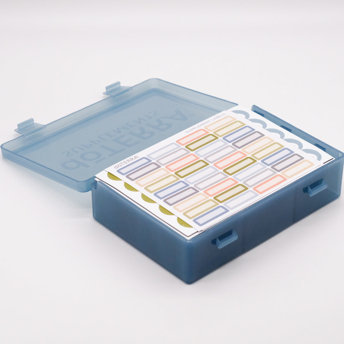 Grand pilulier bleu translucide doTERRA ouvert, avec feuilles d’autocollants colorés rangées à l’intérieur.