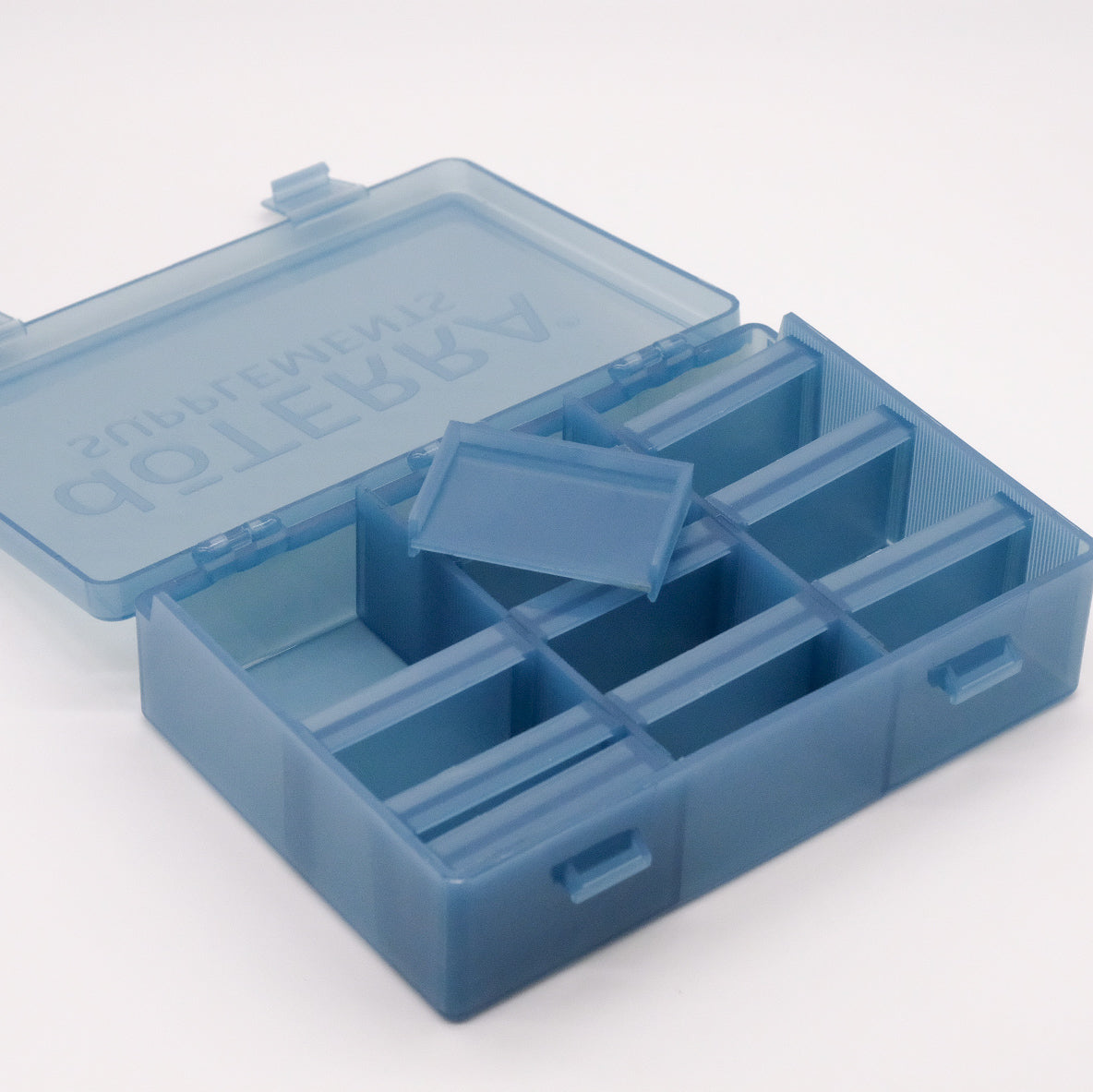 Grand pilulier bleu translucide doTERRA ouvert, avec compartiments vides et séparateur amovible visible à l’intérieur.