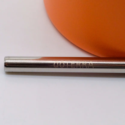 Gros plan sur une paille en métal gravée doTERRA, placée devant une bouteille isotherme orange.
