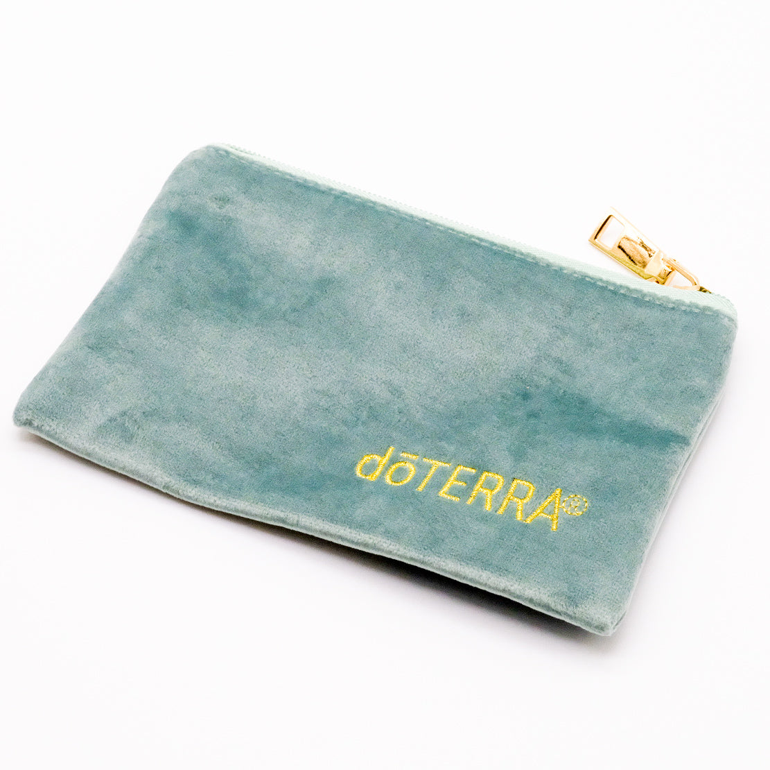 Pochette en velours vert sauge doTERRA avec logo brodé doré et fermeture éclair dorée.