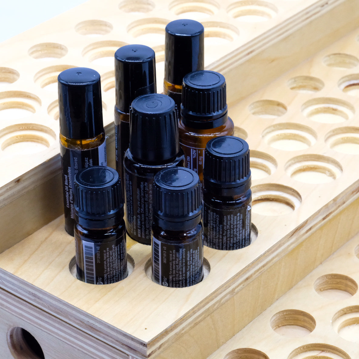 Présentoir en bois à 3 paliers avec plusieurs bouteilles et rouleaux à bille doTERRA insérés dans les emplacements.