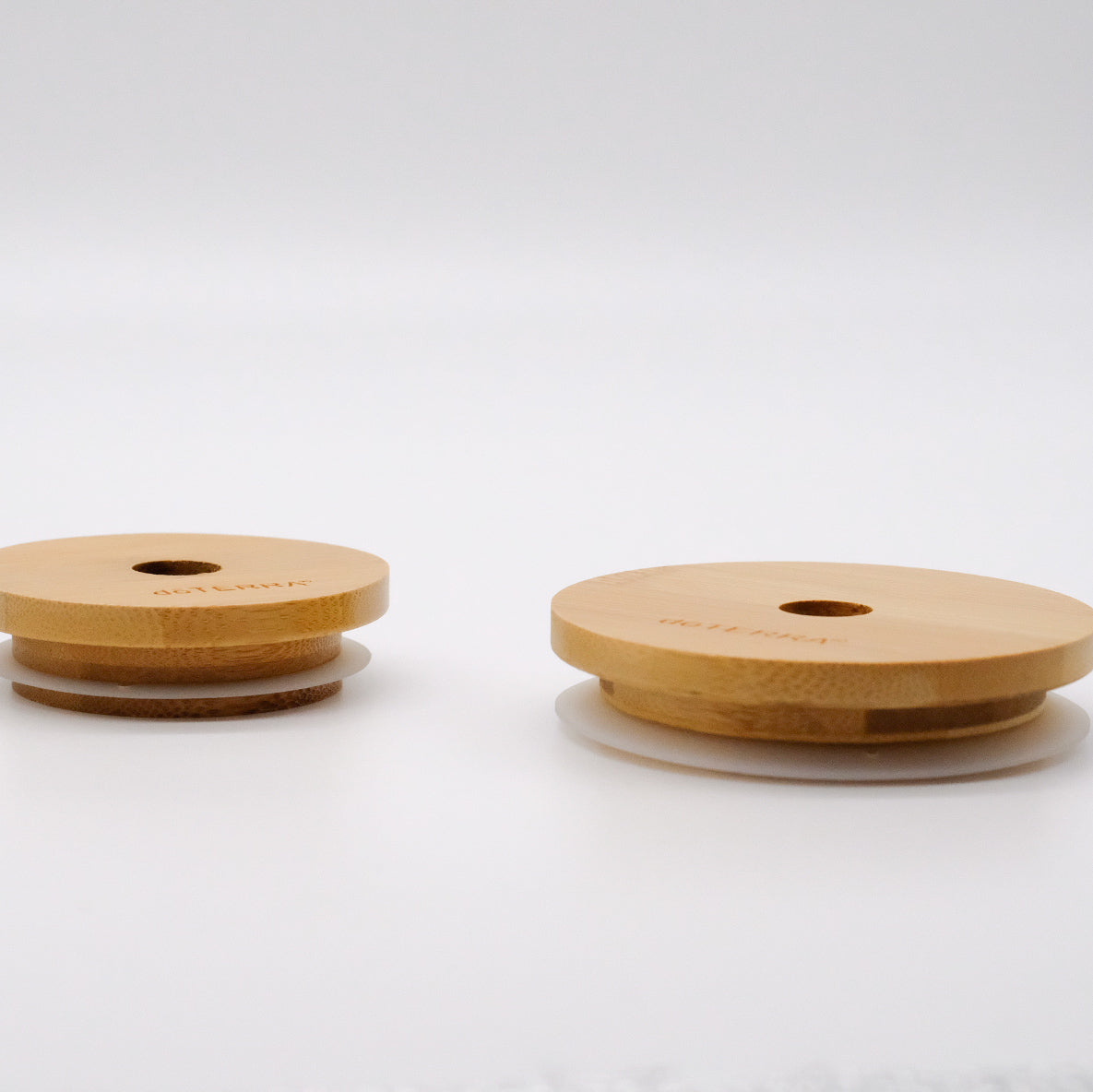 Vue de profil de deux couvercles réutilisables en bambou doTERRA, montrant leur joint en silicone sous la base.